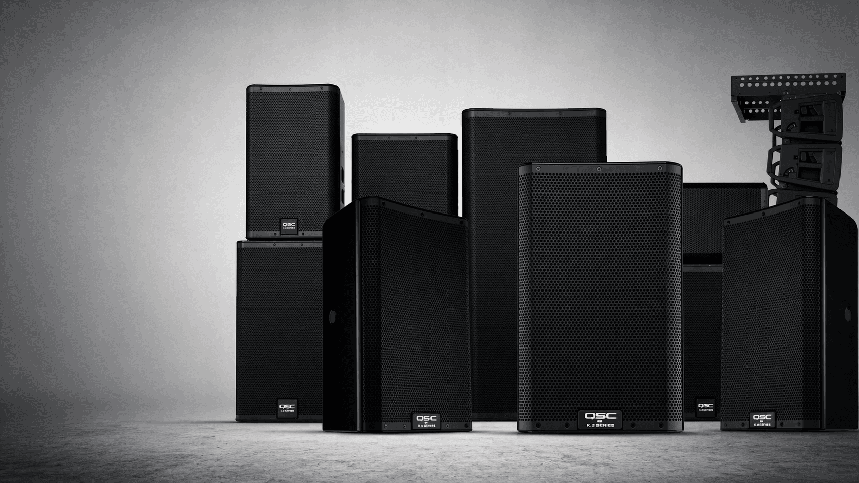 Professional QSC speakers and line array components arranged in a studio banner.